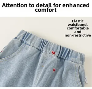 Détail d'un jean bleu clair pour fille avec taille élastique et broderie cœur rouge