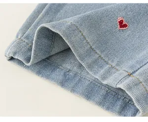 Détail du tissu denim avec broderie de cœur rouge et finitions soignées à double couture