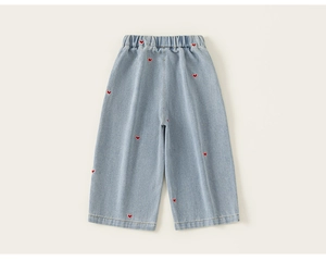 Détail de la broderie cœur rouge sur le jean en denim bleu clair à jambes larges