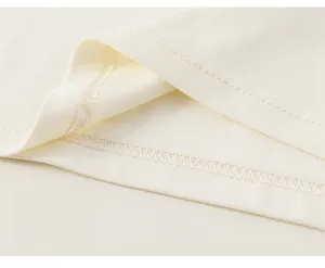 Detailansicht des doppelt genähten Saums und der Baumwolltextur des cremefarbenen T-Shirts