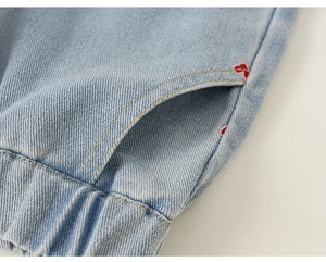 Détail du pantalon en jean bleu clair avec taille élastique et broderie de cœur rouge