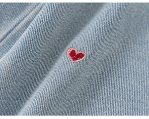 Vue macro du tissu denim bleu clair avec broderie de cœur rouge et rose détaillée