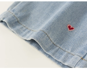Détail de la broderie cœur et de la texture denim sur le jean large bleu clair