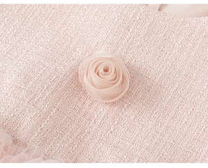 Detailopname van roze tweed stof met zilverdraad en een 3D organza roos op de jurk