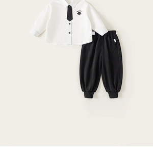 Close-up of white shirt with tie and black joggers featuring dog embroidery detail