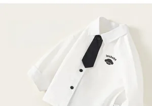 Detail view of the white cotton shirt with black tie and cute dog print for young boys