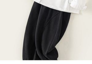 Detailed close-up of white collar shirt and black trousers with fine cotton texture