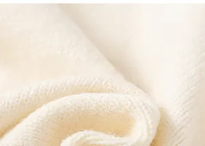 Macro shot of soft off-white knit sweater fabric texture with premium thick knitting details