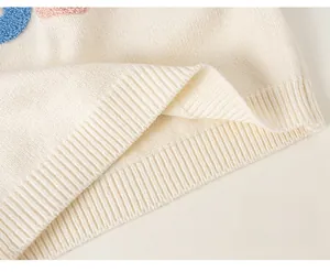 Detailed macro view of the cream knitted sweater with ribbed hem and cute plush embroidery