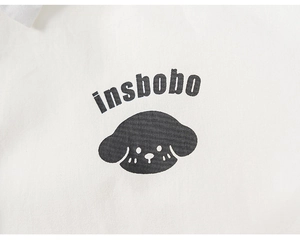 Detail of white cotton fabric with black insbobo text and cute puppy printed illustration