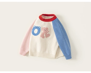 Close-up of children's colorful patchwork knit sweater with plush bear and smiley patch