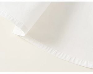 Close-up of fine stitching and hem detail on white cotton school uniform set for boys