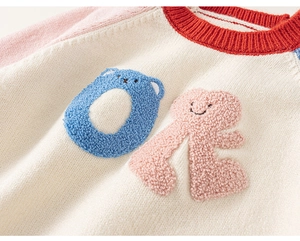 Detail of kids knit sweater showing color block sleeves and soft 3D towel embroidery