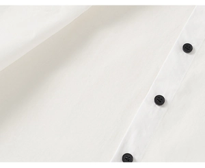 Detailed macro view of white cotton shirt fabric featuring classic black round buttons