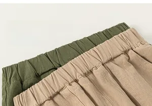 Detail of children's cotton pants featuring an elastic waist in khaki and green