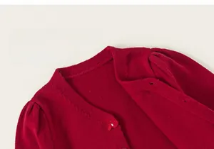 Detail shot of a dark red girls' knit cardigan featuring delicate cherry embroidery