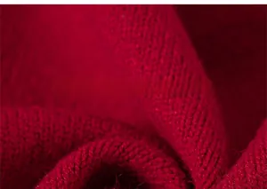 Close-up of the thick red knitted fabric texture and pattern on the girls' cardigan sweater