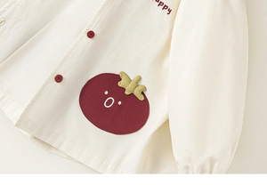 Détail de la veste enfant avec écusson tomate et broderie lettrage happy élégante