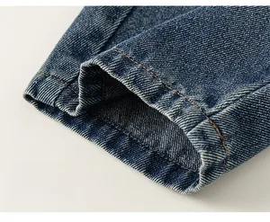 Détail d'un pantalon en denim bleu marine montrant les doubles surpiqûres jaunes et le tissu
