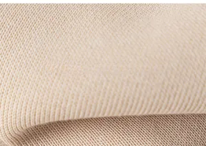 Gros plan sur un tissu en maille beige doux montrant la texture fine et le relief