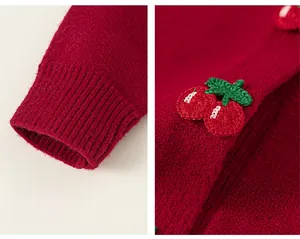 Detail of red knit cardigan featuring handmade cherry crochet and ribbed elastic cuffs
