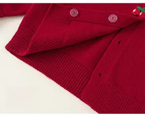 Detail of red girl's knit cardigan featuring ribbed hem and strawberry embroidery