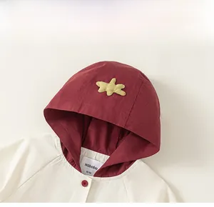 Détail de la capuche contrastée pour enfant avec écusson étoile et étiquette de taille tissée