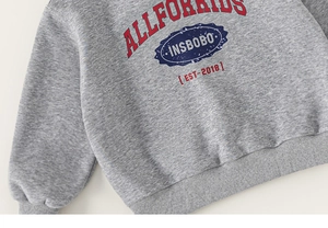 Detail of grey kids hoodie showing vintage athletic print and cotton knit texture