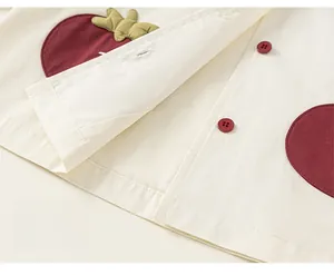 Détails de coutures contrastées, broderie pomme rouge et boutons sur veste beige