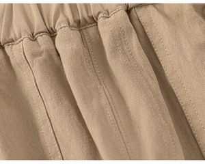 Close-up detail of khaki cotton twill trousers with elastic waist and reinforced stitching