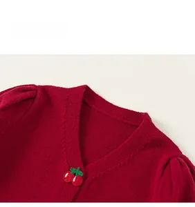 Detail of red girl's knitted cardigan with cute cherry embroidery on the V-neck