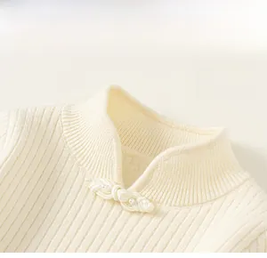 Close-up of knit top featuring a mandarin collar with a delicate white pearl frog button
