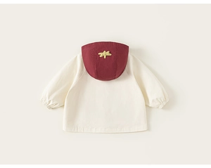 Détail d'une veste à capuche enfant avec empiècements crème et bordeaux et écusson étoile