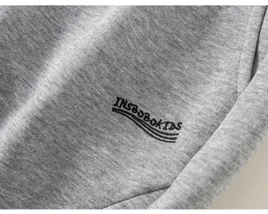 Detail of grey knitted fabric with INSBOBOKIDS letter print on casual boys joggers