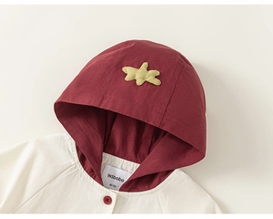 Détail du col d'une veste à capuche pour enfant avec bouton rouge et étoile