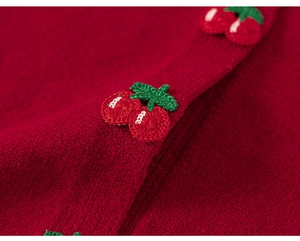 Detailed macro view of 3D crochet cherry embellishment on red knitted girls cardigan