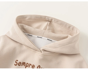 Détail du col d'un sweat à capuche en coton avec texture tricotée et imprimé marron