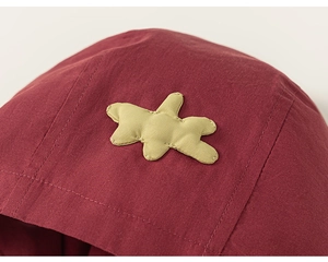 Détail d'une veste à capuche rouge foncé avec écusson étoile jaune et texture sergé