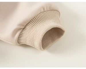 Vue macro détaillée des poignets côtelés élastiques sur un sweat à capuche beige