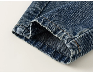 Vue macro d'un jean bleu foncé montrant les doubles coutures orange et le sergé fin