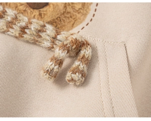 Détail macro du sweat à capuche enfant avec cordon tressé et texture tricotée de qualité