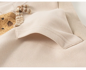 Gros plan d'un sweat à capuche beige enfant avec patch ours en peluche et écharpe