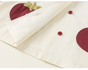 Détail de veste enfant montrant la texture coton-lin et la poche pomme rouge