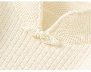 Detail of knit sweater collar featuring traditional Chinese button knot and pearl accents