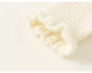 Detail of cream-colored ribbed knit sleeve with fluffy faux fur and lettuce edge trim