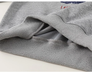 Close-up of light gray ribbed hem and stitching on children hooded sweatshirt