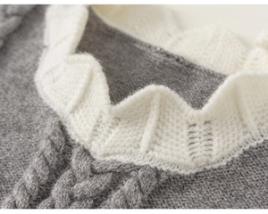 Close-up of gray cable-knit sweater vest featuring elegant ruffled white collar detail