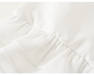 Detail van witte katoenen top met drielaagse ruches van chiffon en verfijnde stiksels