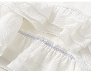 Detailopname van witte chiffonlagen met gelaagde ruches en fijne paarse stiksels op de stof