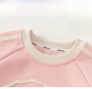 Detail of pink toddler sweatshirt featuring ribbed crew neck and striped shoulder accents
